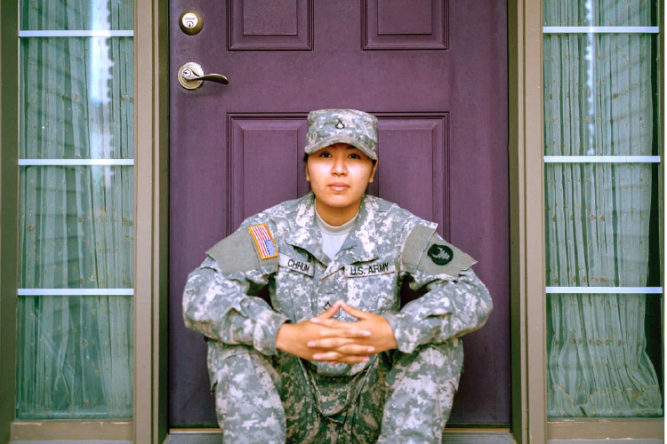 A photo of a female U.S. military member sitting on the front steps of a house.